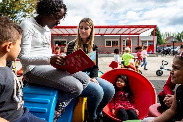 Kinderen lezen op de speelplaats in stedelijke basisschool Edison